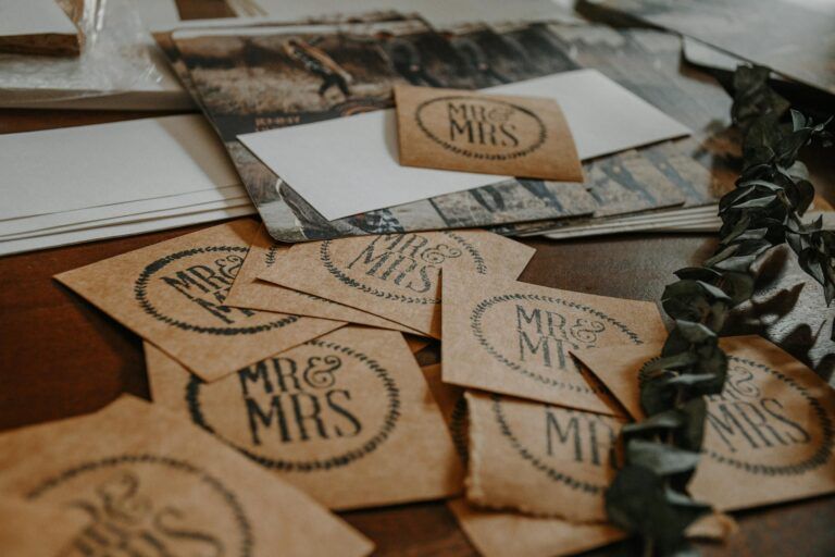 A collection of rustic wedding invitation cards with 'Mr & Mrs' text on a wooden table.