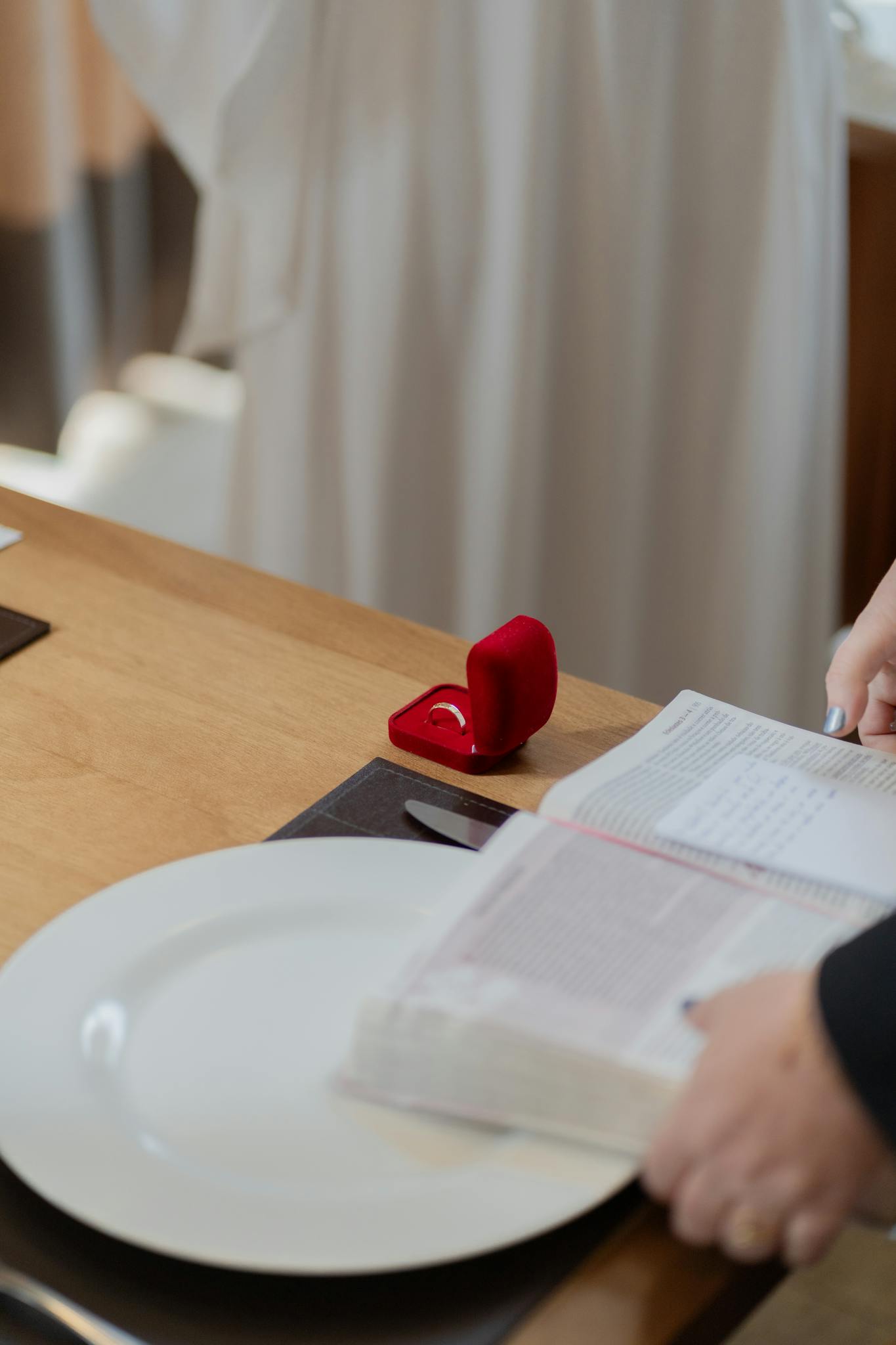 A romantic table setup featuring an open ring box and a book, ideal for proposals.
